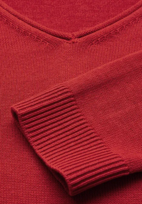 Roter Strickpullover mit V-Ausschnitt, Detailansicht von Ärmel und Kragen.